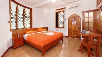 Un dormitorio con una cama de madera, una mesita de noche, una silla de madera y una puerta de madera con un ventanal.