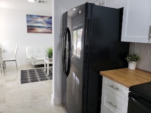 Eine moderne Küche mit einem schwarzen Kühlschrank, weißen Schränken und einer Holzauskleidung.