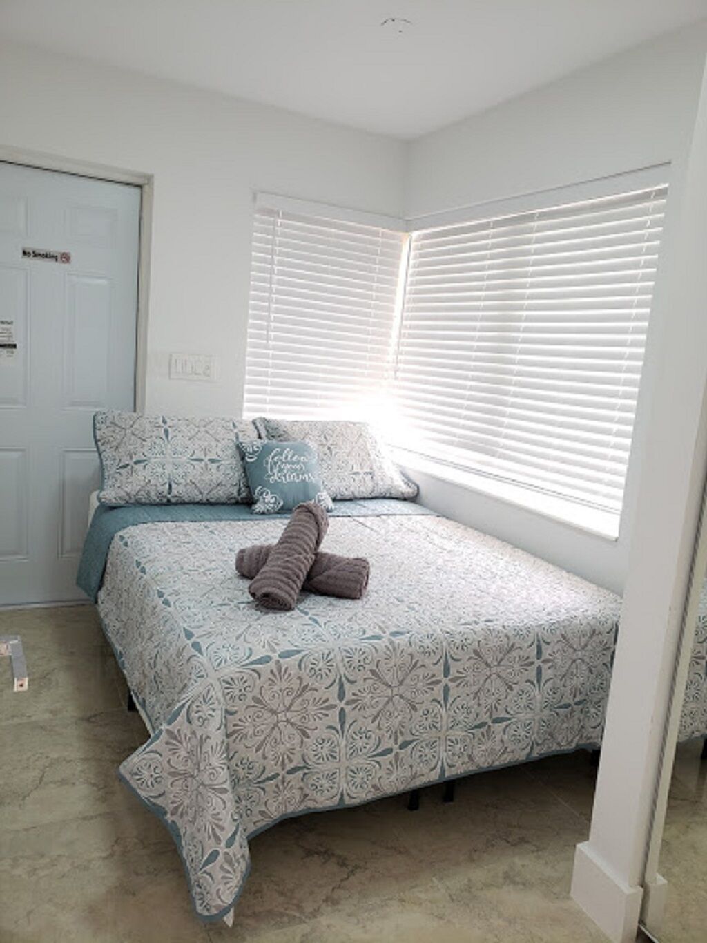 A bedroom with a bed, pillows, and a rolled-up towel.