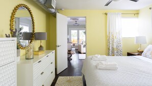A hotel room with a bed, a vanity with a mirror, a ceiling fan, and a view of the outdoor seating area. - Blue Tempo - Steps to Wilton Dr, Heated Salt Pool, Huge Yard (Wilton Manors)