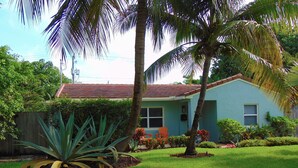 A house with a red roof, surrounded by a well-maintained lawn and various plants. - Blue Tempo - Steps to Wilton Dr, Heated Salt Pool, Huge Yard (Wilton Manors)