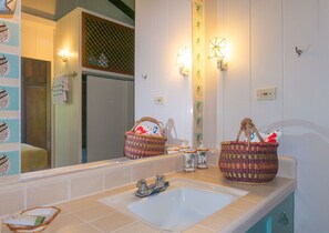 Un baño con un espejo grande, dos cestas sobre el lavabo y luces empotradas en la pared.