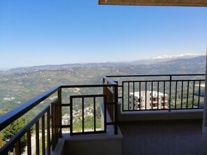 A balcony with a metal railing overlooking a mountainous landscape with buildings in the distance. - Bhamdoun Residence (Bhamdoun)