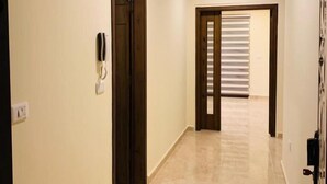 Un passadís amb sostre de fusta i parets beix, que condueix a una habitació amb finestra i porta.
