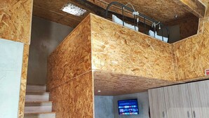 A modern interior with a wooden staircase, a kitchen area with a tiled backsplash, and a flat-screen TV mounted on the wall. - Ruby Charm Houses 8 66132/AL (Porto)