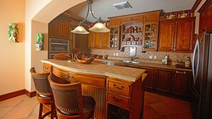A kitchen with a large island, wooden cabinets, and a stainless steel refrigerator. - Luxury Ground Floor  Condo, close to pool access to beach club at Los Suenos. (PUNTARENAS)