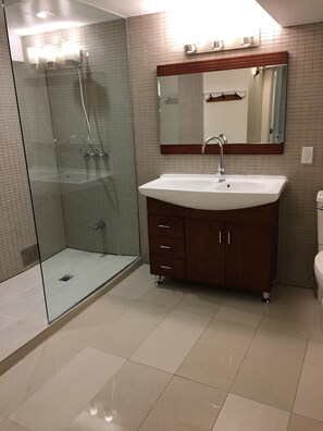 A bathroom with a glass-enclosed shower, a white sink with a wooden vanity, and a large mirror above the sink.