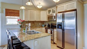 A kitchen with granite countertops, stainless steel appliances, and pendant lighting.
