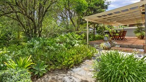 A covered patio area with a table and chairs, surrounded by lush greenery and trees. - Miriam's Cottage Self Contained 2 bedroom cottage (Tanunda)
