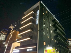 A hotel with a modern facade, a visible entrance, and a sign indicating a parking area. - Hotel Live Max Nagoya Sakuradori (Nagoya)