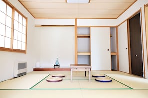 A traditional Japanese room with tatami flooring, a tatami mat table, and a sliding door.