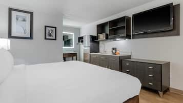 Une chambre moderne avec un grand lit, une armoire intégrée, un téléviseur à écran plat et une petite kitchenette.