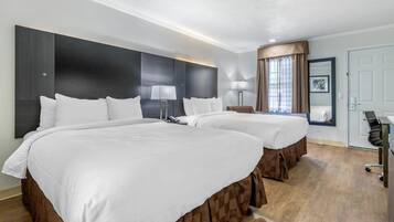 Une chambre d’hôtel avec deux lits, un bureau, une chaise, une lampe et un grand miroir.
