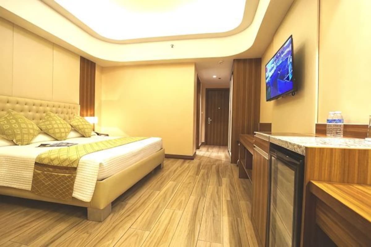 A hotel room with a bed, a television, a desk, and a bathroom.