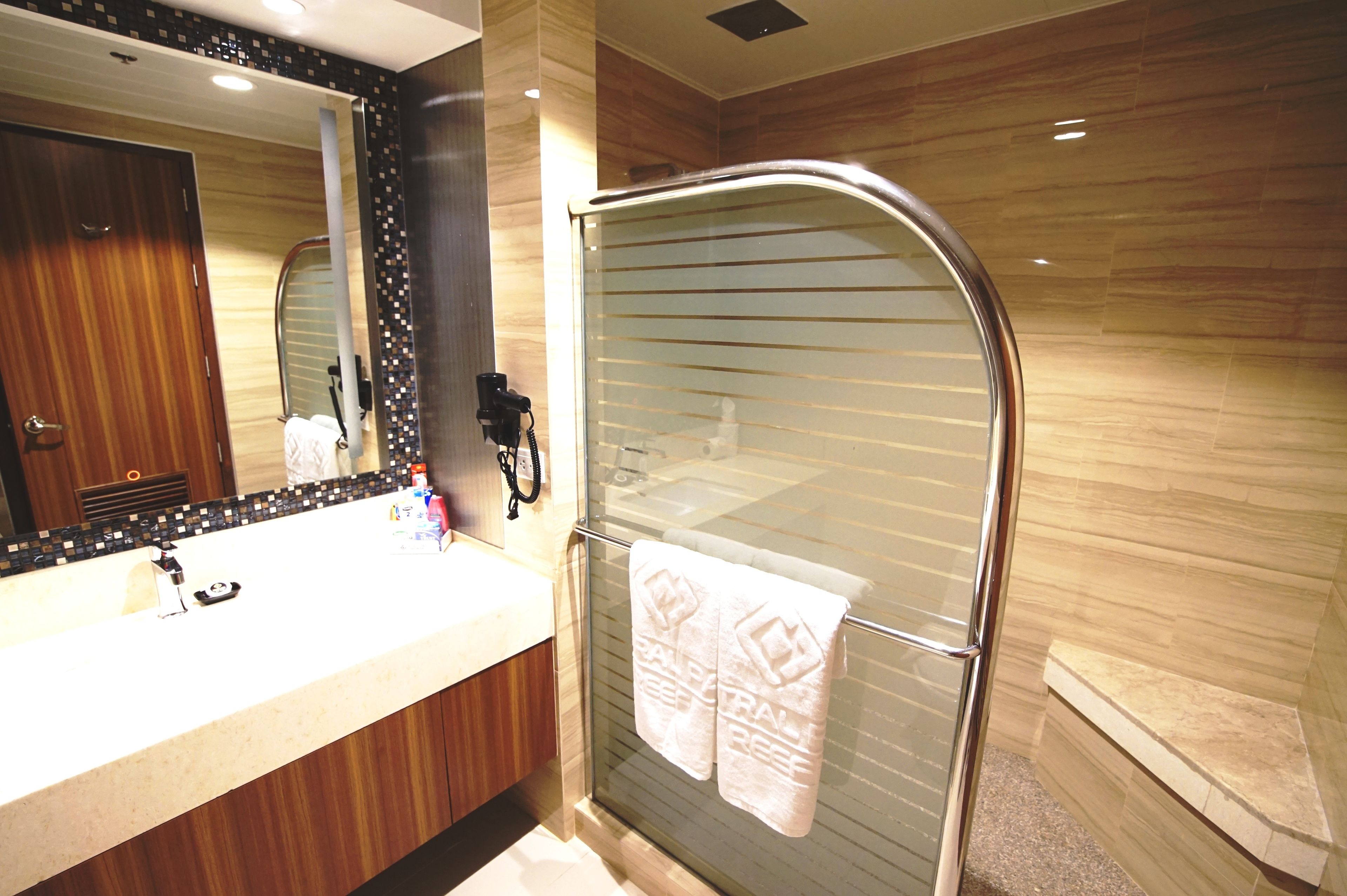 A modern bathroom with a glass shower enclosure, a vanity with a mirror, and a towel rack with towels.