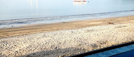 Une plage avec des bateaux, un rivage sablonneux et une vue dégagée sur l’eau.
