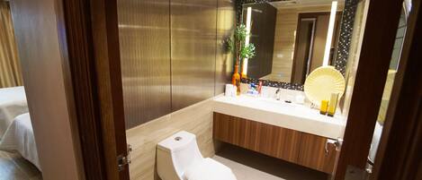 A modern bathroom with a white toilet, wooden vanity, and a large mirror.