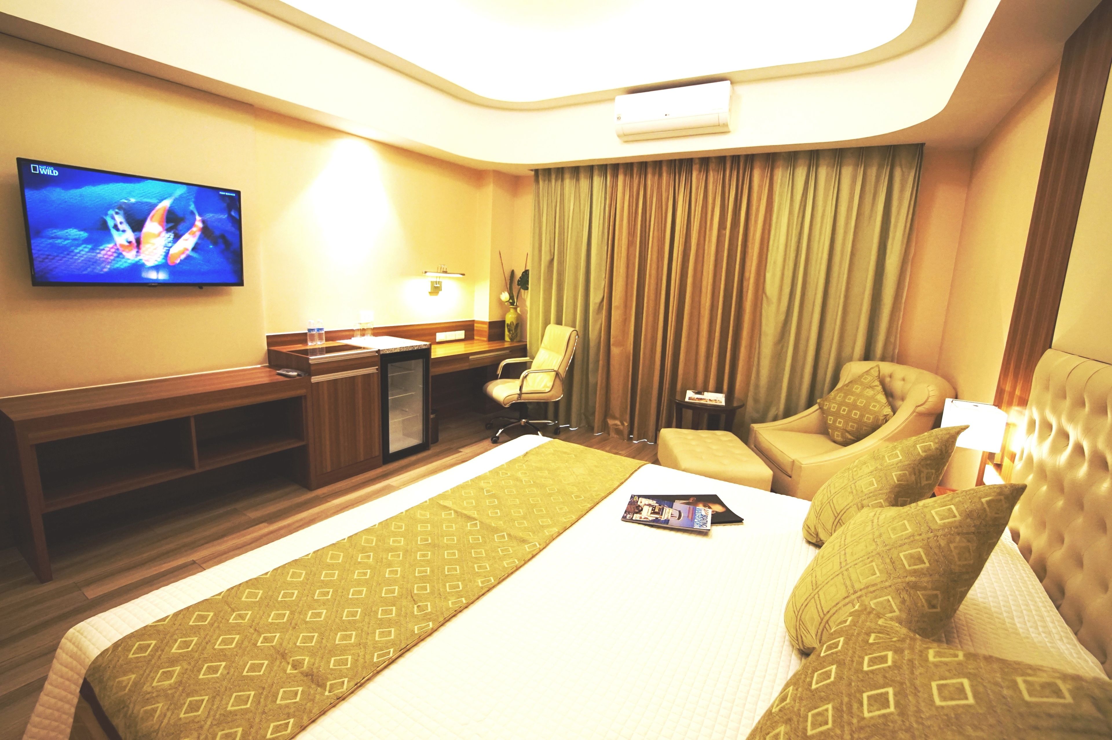 A hotel room with a bed, a desk, a TV, a chair, and a sofa.