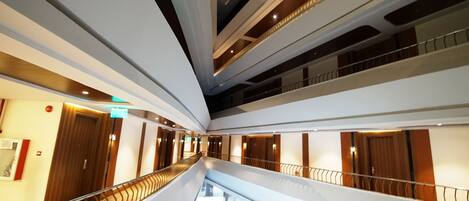 A multi-level interior with a central staircase, railings, and a series of doors and windows.