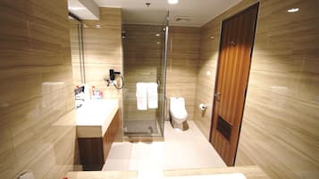 Un baño moderno con ducha de vidrio, tocador de madera y un inodoro.