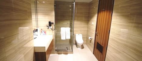 Un baño moderno con ducha de vidrio, tocador de madera y un inodoro.