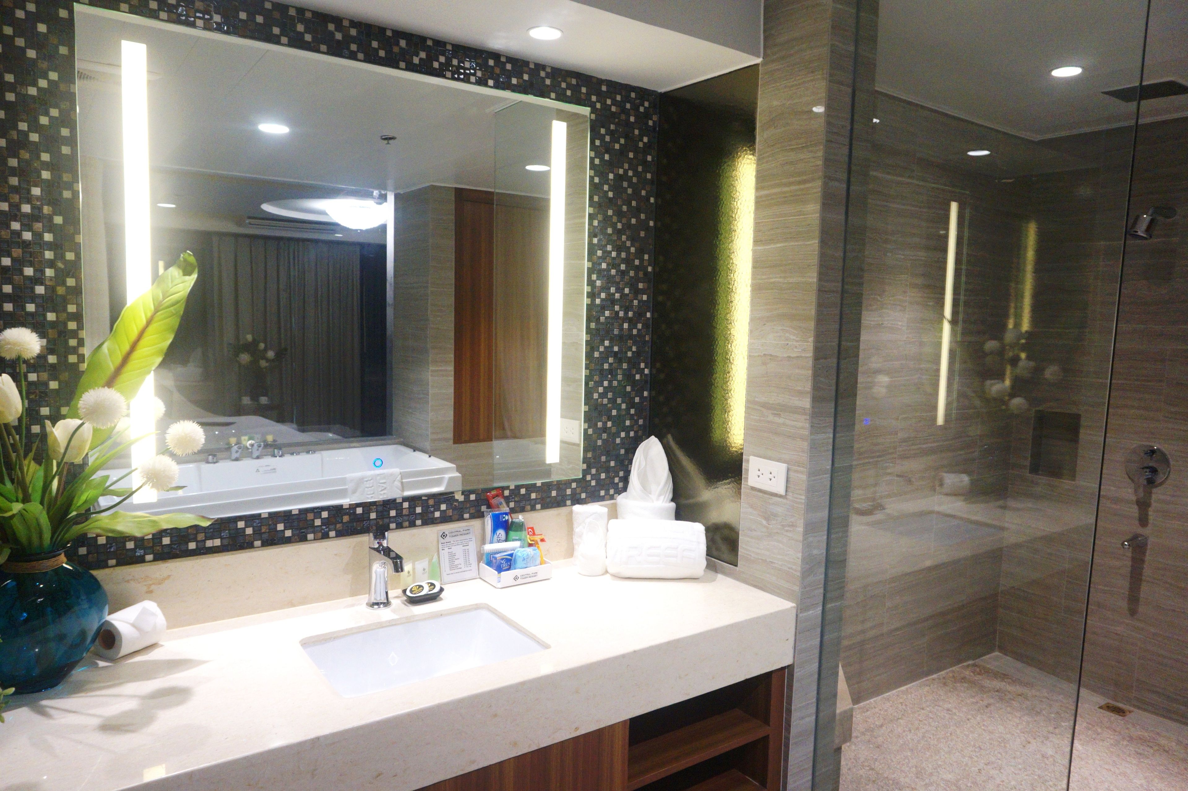 A modern bathroom with a large mirror, a sink, and a glass-enclosed shower.