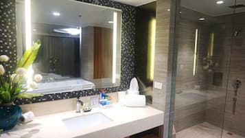 A modern bathroom with a large mirror, a sink, and a glass-enclosed shower.