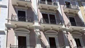 A multi-story building with balconies, a garage door, and parked cars. - Azzurra Flat Bari Center (Bari)