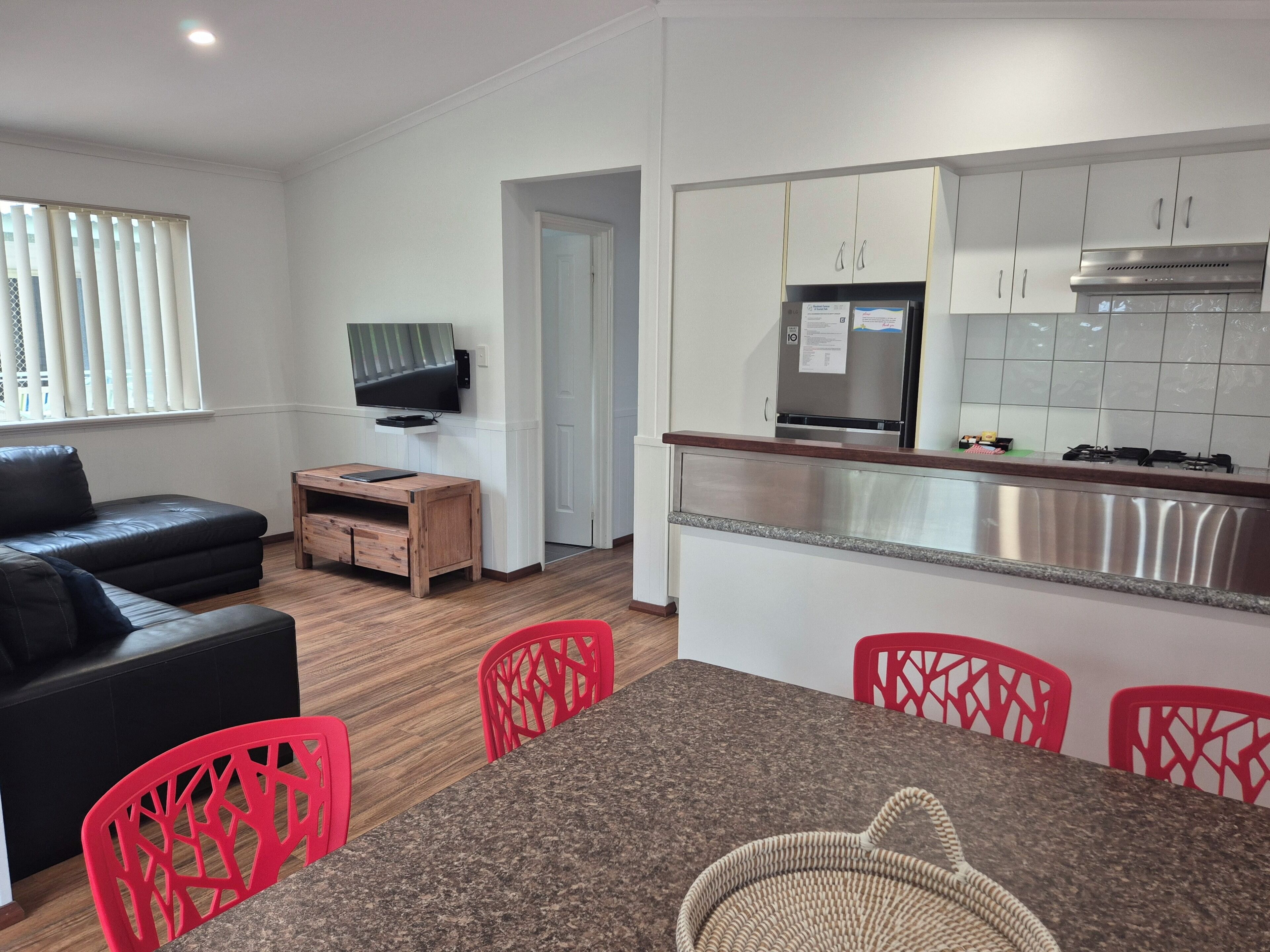 A modern living room with a sofa, a TV, and a dining area with chairs and a table.