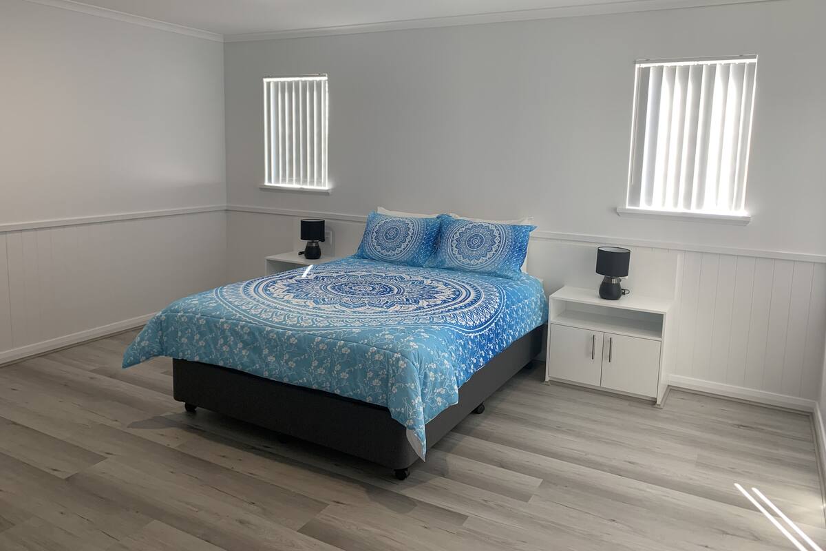 A bedroom with a bed, two nightstands, a window, and a ceiling light.