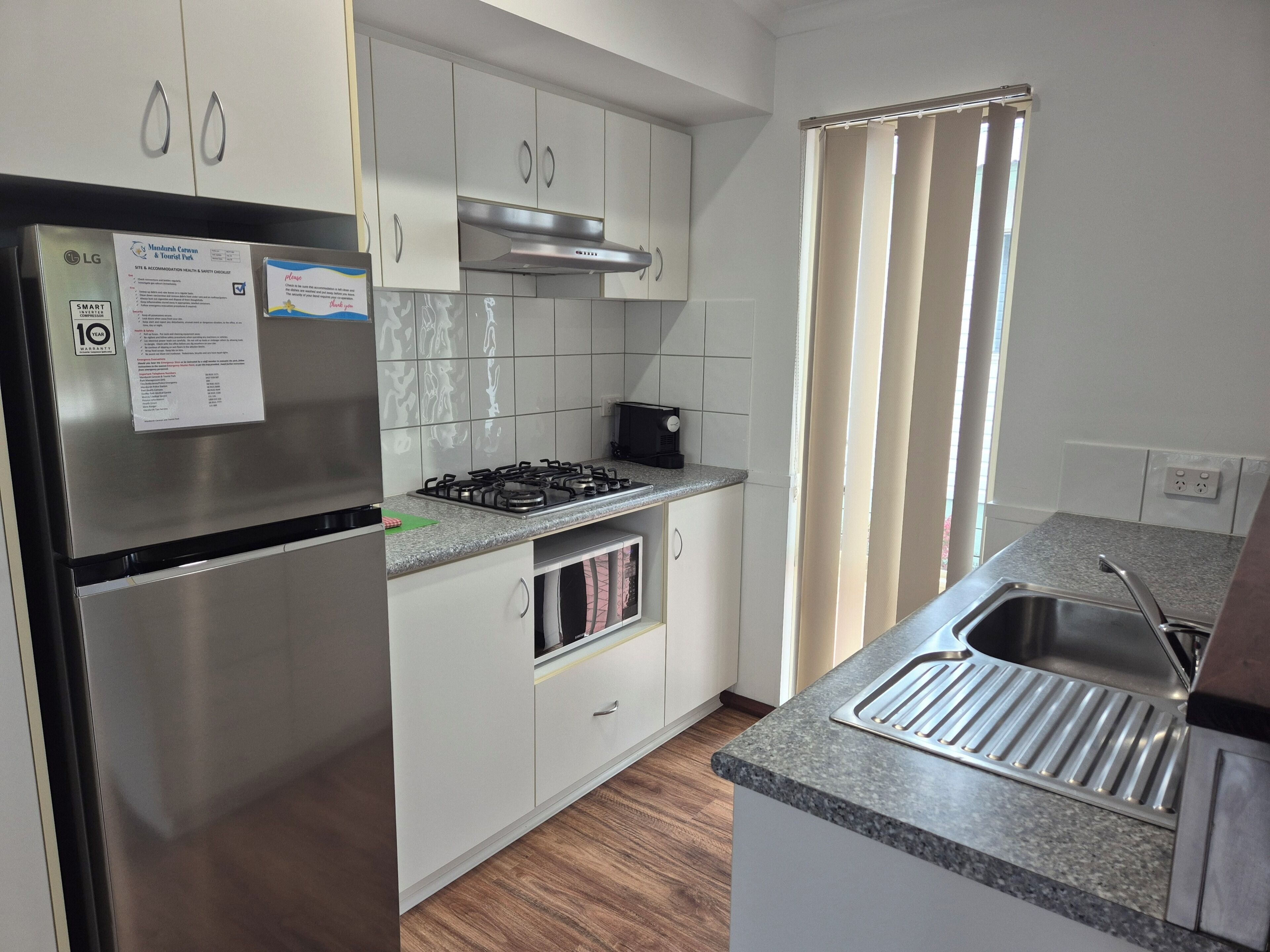 Uma cozinha moderna com eletrodomésticos de aço inoxidável, armários brancos e uma janela com cortinas.