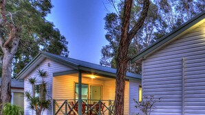 A single-story building with a porch, large potted plants, and a tree in front. - Mandurah Caravan & Tourist Park (Furnissdale)