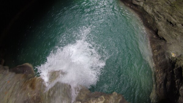 A rocky cave entrance with a pool of water. - Alegria Water Front Beach House (Alegria)