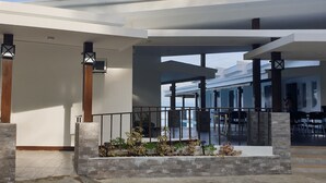 Un espacio exterior moderno con una jardinera de piedra, barandas de metal y vista al mar.