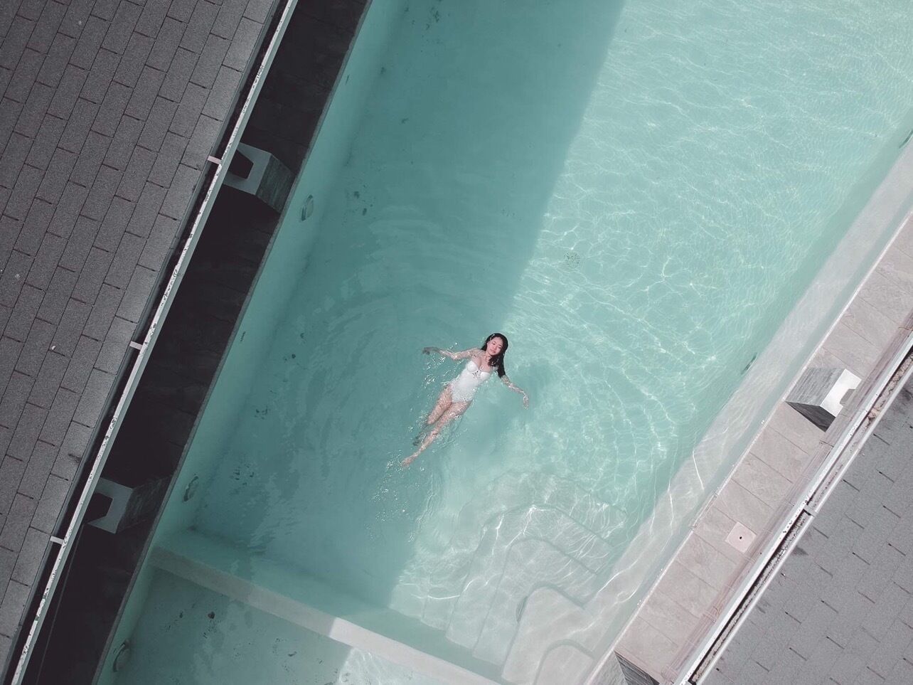 Una persona nadando en una piscina rectangular con agua cristalina.