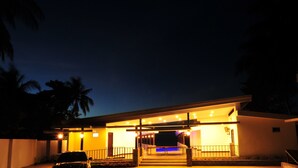 Un edificio moderno con una entrada bien iluminada y un área de piscina.