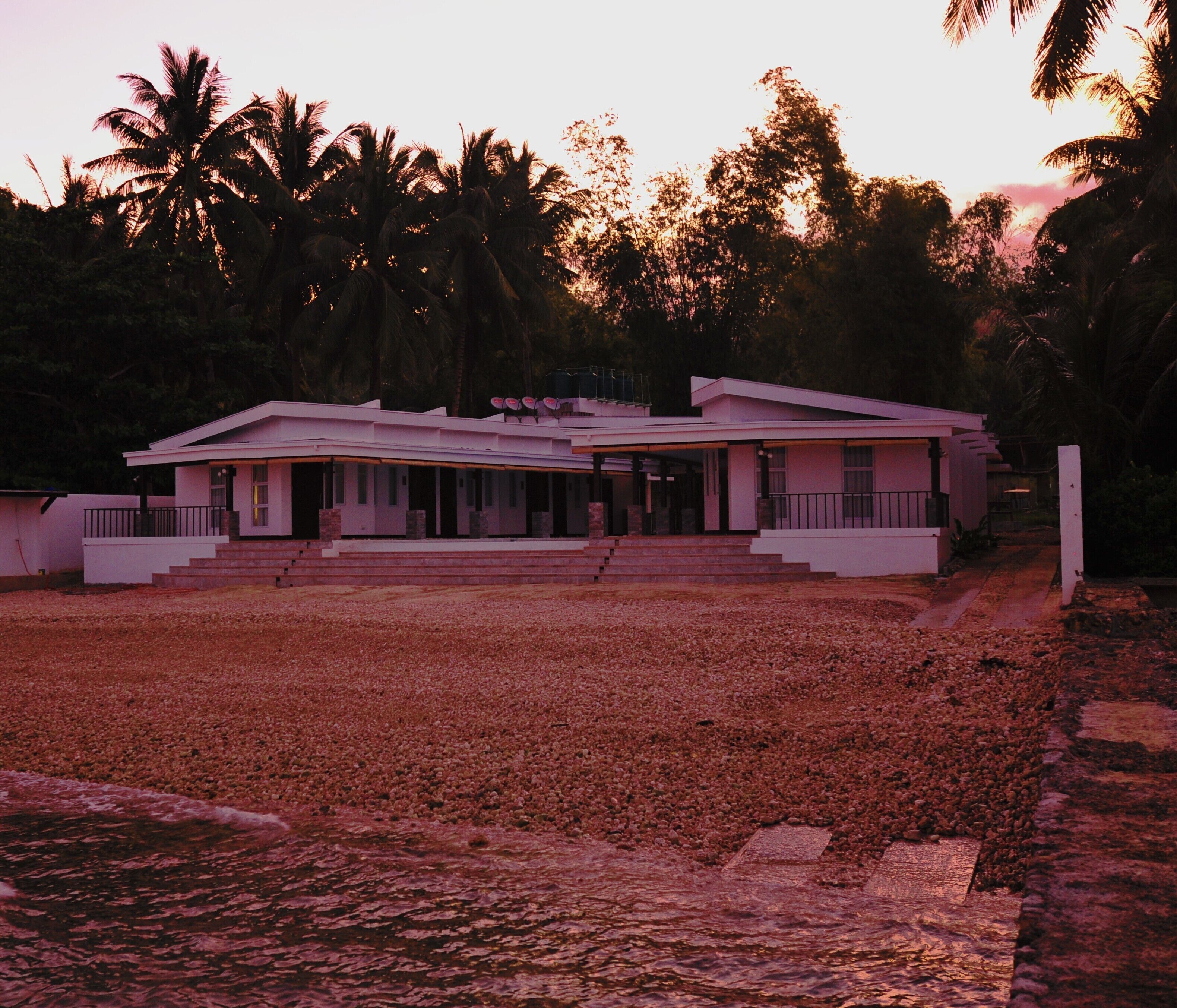 A modern two-story house with a flat roof, a covered porch, and a paved driveway.