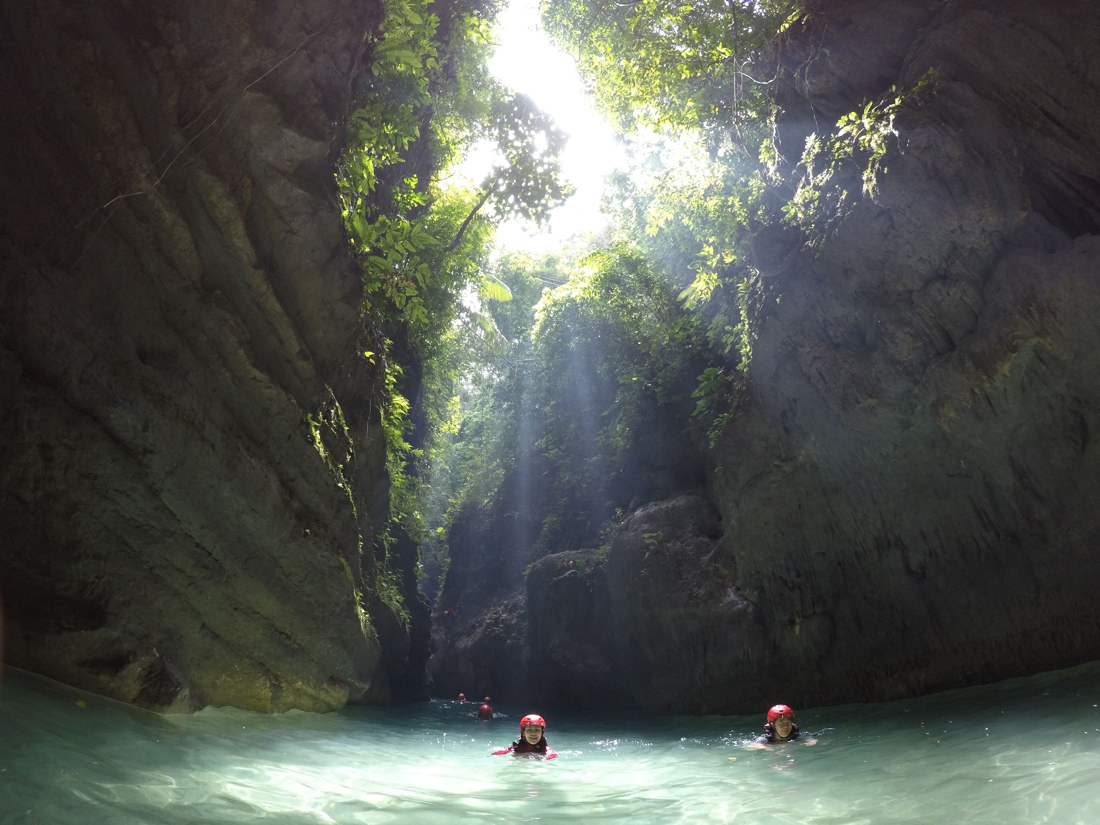 Una cueva con agua, paredes de roca y gente nadando.