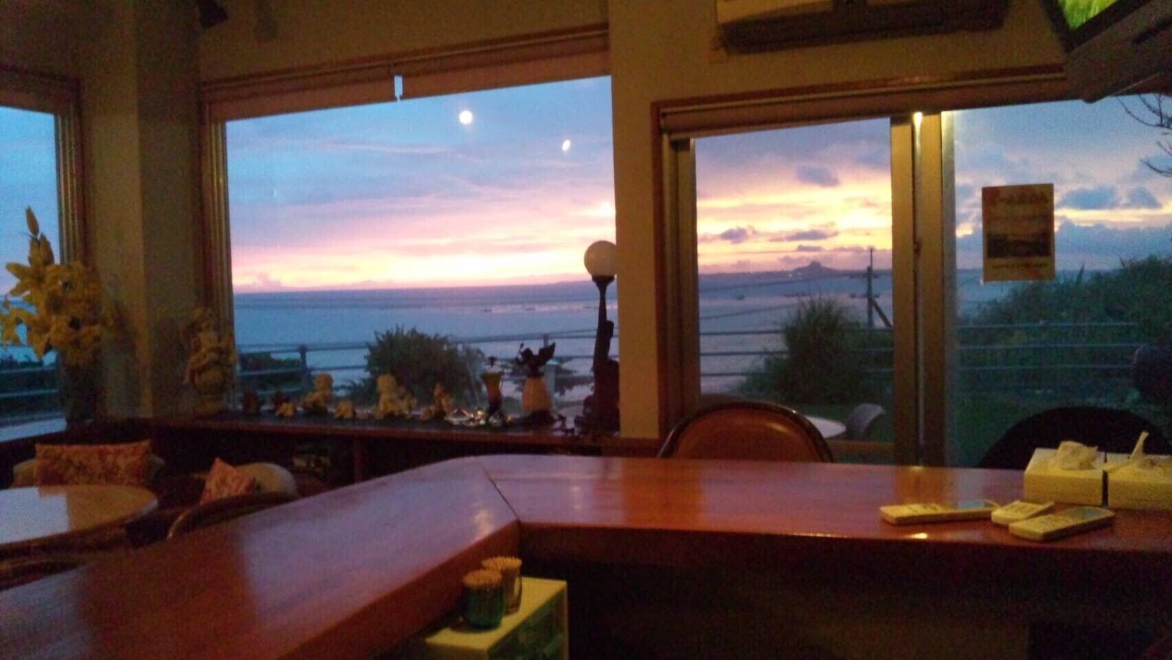 Un restaurant amb vistes al capvespre sobre l'oceà, una zona de bar i una disposició de seients amb taules i cadires.