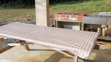 A concrete pillar, a checkered table, and a brick oven in an outdoor setting.