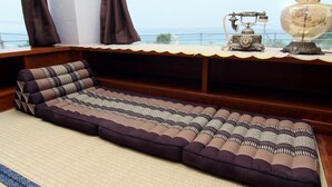A room with a large window, a sofa, a lamp, and a decorative item on the windowsill. - Minshuku Tantawan (Motobu)