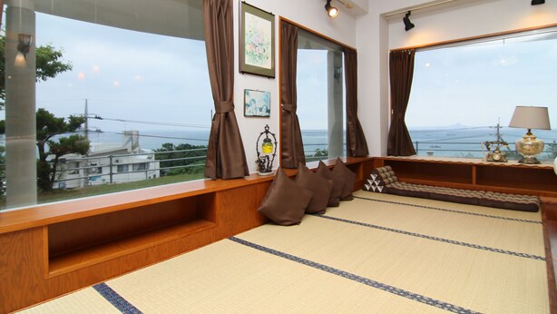 A room with a large window, a wooden bench, and a tatami mat floor. - Minshuku Tantawan (Motobu)