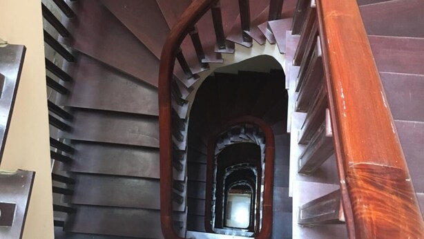 Un escalier en bois, doté d’une rampe, mène à un palier.