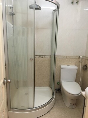 A bathroom with a glass-enclosed shower, a toilet, and a tiled floor. - Sunrise Hotel (Hanoi)