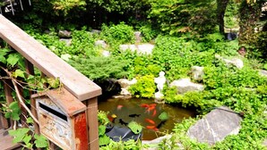 Um jardim tranquilo com lago, ponte de madeira e vegetação exuberante.