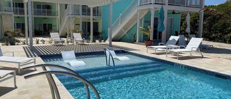 A swimming pool with a 3 ft 8 in depth, surrounded by lounge chairs and a covered area with stairs leading to a balcony.