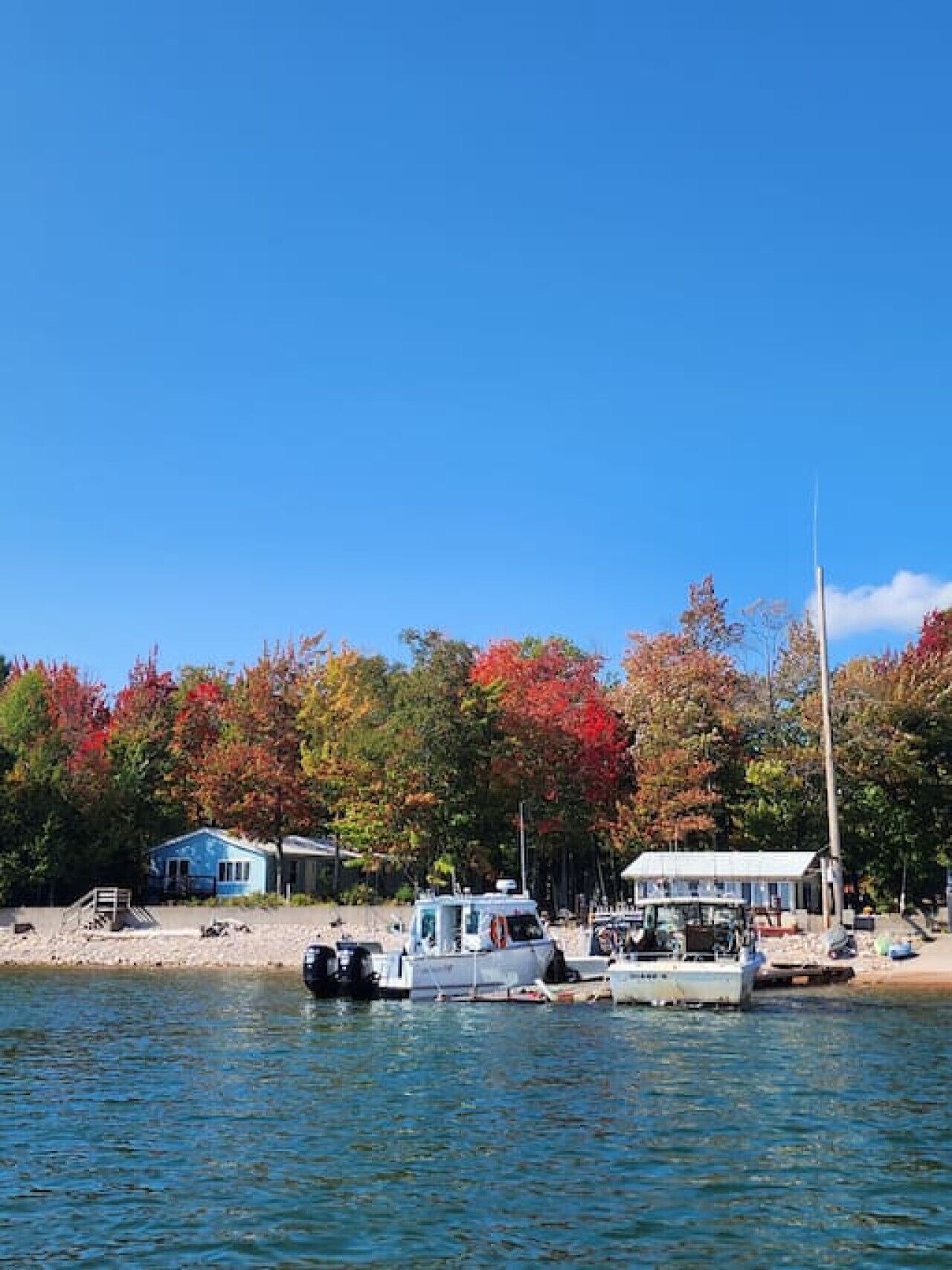 A lakeside property with a dock, boats, and a small cabin.