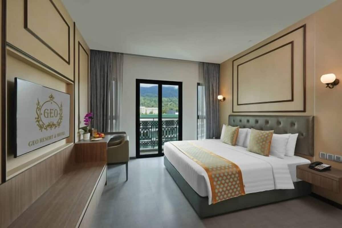 A hotel room with a bed, a desk, a chair, a TV, and a balcony with a view.
