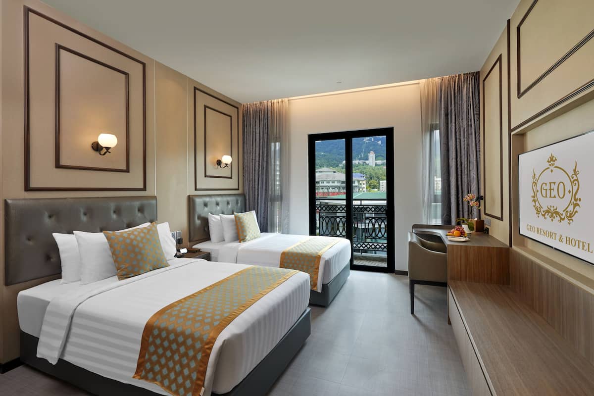 A hotel room with two beds, a balcony with a view, and a reception desk.