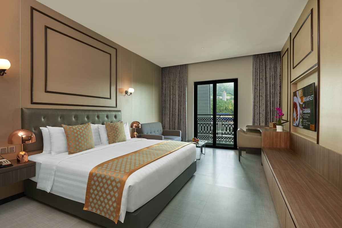 A hotel room with a large bed, a desk, a chair, a TV, and a balcony with curtains.
